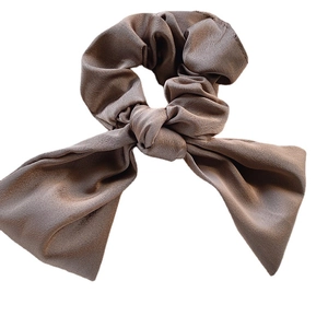Brown satin scrunchie with a large bow showing elegant silk texture and soft pleats