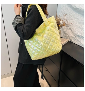 Detail der gesteppten neongelben Metallic-Tasche mit Laser-Textur auf schwarzem Mantel