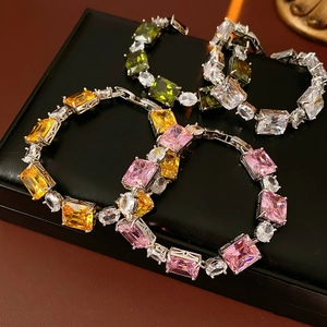 Macro shot of colorful square zircon bracelets in pink, yellow, and green on black leather
