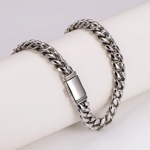 Polished silver stainless steel Cuban link necklace with rectangular clasp on white stand