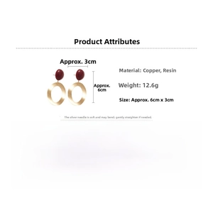 Detail view of oval brushed gold earrings with dark red resin beads, 6cm long