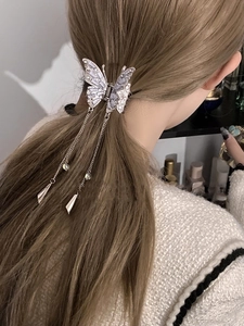 Detailed close-up of a silver butterfly hair claw with tassels and rhinestones on hair