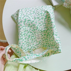 Detail of floral canvas tote bag with a white woven label on a clean desk