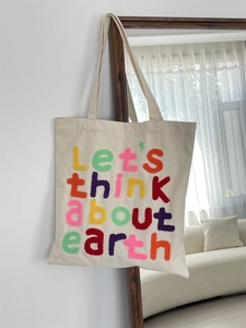 Detail of colorful towel embroidery lettering on cream canvas tote bag with long handles