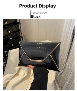 Detail of black crocodile embossed envelope clutch with elegant gold metal edge trim