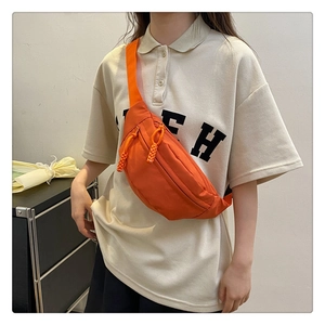 Close-up of orange canvas chest bag featuring zipper with woven cord pull detail
