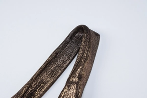Gros plan du licou en bronze métallisé montrant la texture tissée et les surpiqûres