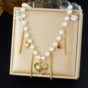 Dettaglio di collana di perle di lusso con ciondoli smaltati a farfalla, fiore e cuore