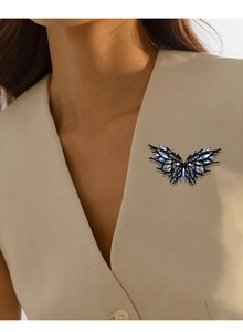 Detail of dark butterfly brooch with blue crystals on a beige suit lapel
