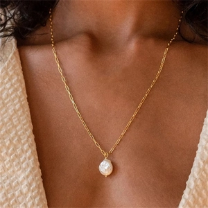 Detalle de collar en Y de acero dorado con colgante de perla barroca de agua dulce natural