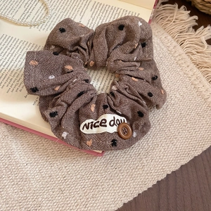 Brown polka dot scrunchie with button and 'Nice day' label on vintage books