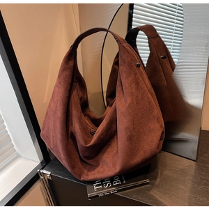 Detail of a large brown matte faux suede hobo tote bag against a mirror reflection