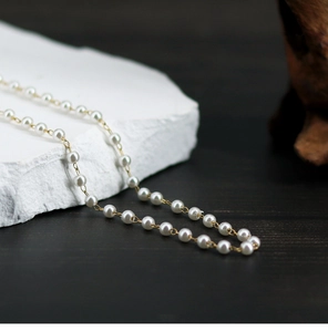 Macro detail of elegant white pearls and gold chain links on a textured stone surface
