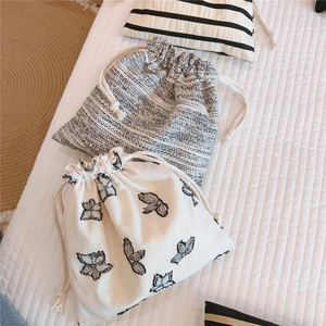 Detailed view of cream butterfly print and grey tweed drawstring fabric storage bags