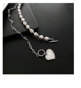 Detail of layered necklace featuring baroque pearls, heart pendant, and T-bar clasp