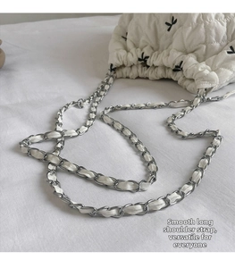 Detail of leather-intertwined chain strap on white quilted floral bucket handbag