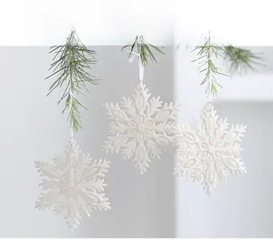 Close-up of white glitter snowflake ornaments hanging on green Christmas pine branches