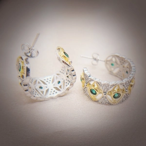 Detailed macro shot of vintage two-tone earrings with green emeralds and white diamonds