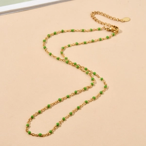 Detailed macro of gold link chain with green enamel beads and adjustable clasp detail