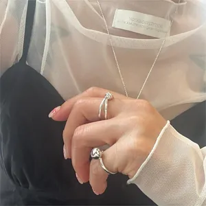 Detailed view of silver minimalist knot rings and a matching fine chain necklace on model