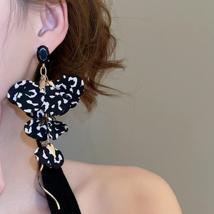 Detailed view of leopard print fabric flower earrings with blue gemstone on model