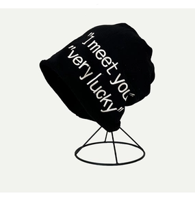 Dettaglio del berretto in maglia nera con ricamo bianco meet you very lucky su supporto