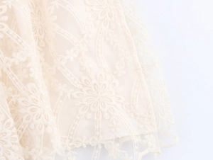 Macro shot of delicate floral lace layering and mesh texture on a beige bohemian dress