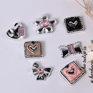 Detailed macro view of seven Y2K silver metal charms with pink and black enamel details