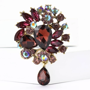 Close-up of vintage gold alloy brooch featuring dark red and purple crystal gemstones