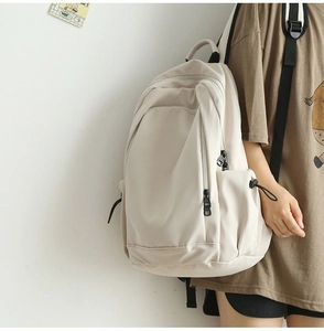 Side view of a minimalist beige nylon backpack with multi-layer storage on a model