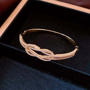 Vue macro d'un bracelet nœud plaqué or serti de zircons blancs dans un coffret velours