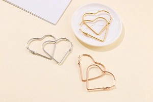 Detailed macro view of large heart hoop earrings with twisted rope texture in three colors