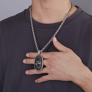 Detail of silver wolf head relief pendant with twist chain on grey t-shirt