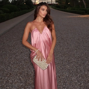 Detail of pink silk slip dress with elegant pearl clutch on a manor gravel path