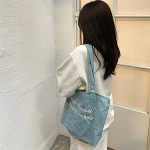 Detail of embroidered Blue Monday Friday feeling text on blue denim canvas tote bag