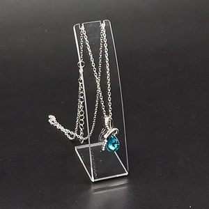 Detailed close-up of blue teardrop gemstone pendant on acrylic display stand