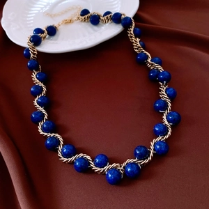 Detail of vintage gold twisted chain wrapped around lapis lazuli blue stone beads