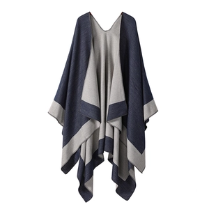 Detail of navy blue and gray double-sided knitted poncho with striped contrast edging
