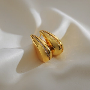 Detailed macro view of gold-plated teardrop earrings with shimmering cubic zirconia stones