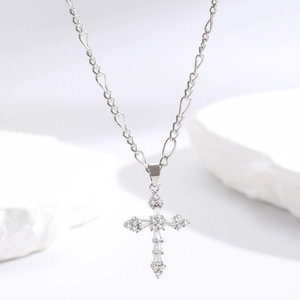 Close-up of silver cross necklace with cubic zirconia pendant on white stone
