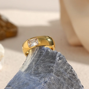 Detailed macro shot of 18K gold plated ring with rectangle zircon on a grey stone