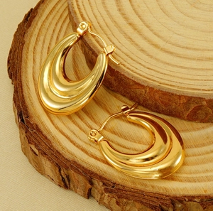 Detailed view of polished 18K gold-plated chunky hoop earrings on rustic wooden rings