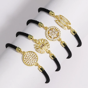 Detail of four black braided rope bracelets featuring gold-plated zircon charms on display