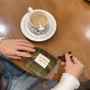 Detailed macro view of olive green plush felt pouch on a rustic wooden table surface