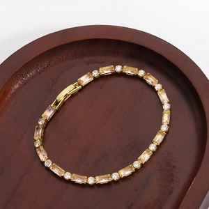 Dettaglio di un bracciale dorato con zirconi rettangolari rosa e cristalli bianchi