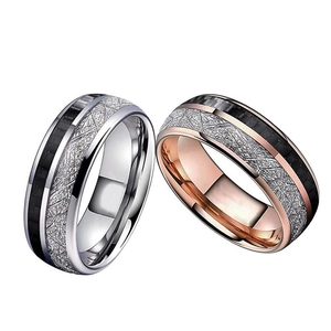 Macro detail of 8mm stainless steel rings featuring black carbon fiber inlay and meteorite texture