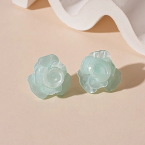 Detail of 3D mint green resin rose earrings with a shimmering iridescent finish and petals