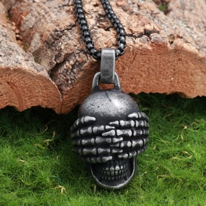 Detailed close-up of a vintage stainless steel skull pendant on natural mossy bark