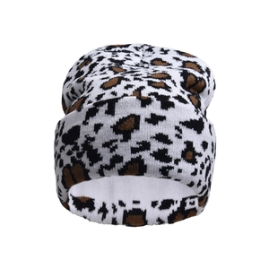 Detailed close-up of cow print knit beanie fabric showing soft texture and pattern