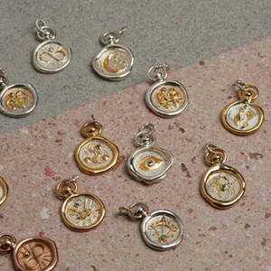 Macro detail of vintage wax seal zodiac pendants with embossed symbols and turquoise stone